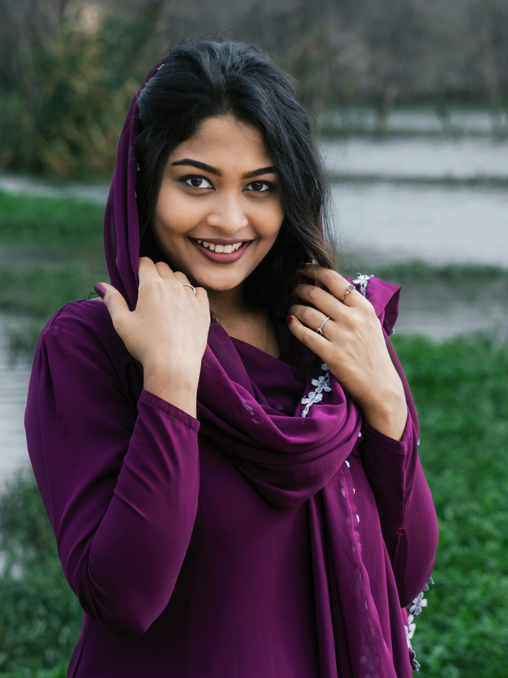 Portrait of a smiling woman wearing a purple dress standing by a riverside.